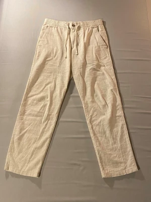 Beiga linnebyxor - Beiga linnebyxor, regular fit, från H&M. Luftiga med resår i midjan. Tillverkade i ett lätt och svalt linnematerial. Knappt använda pågrund av att storleken inte passade mig.