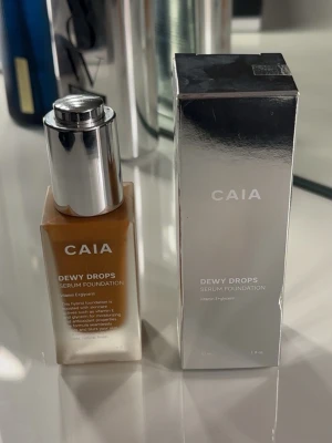 CAIA Dewy Drops Serum Foundation - Foundation från CAIA i nyansen Dewy Drops. Kommer i en lyxig fyrkantig glasflaska med silvrig pump och tillhörande silvrig kartong. Ger en återfuktande och fräsch finish med vitamin E och hyaluronsyra. Perfekt för dig som vill ha en naturlig glow. KOMMER med förpackning testat 2-3 gånger ej min färg tyvärr:(