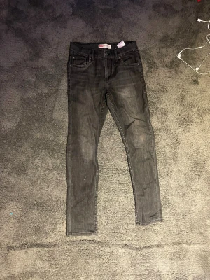 Svarta slim jeans från Levi's - Säljer ett par svarta jeans från Levi's med klassisk femficksdesign och dragkedjegylf. Jeansen har en lätt tvättad look och smal passform som sitter tajt hela vägen ner. Perfekta till sneakers eller boots. Modell 512 storlek 14a