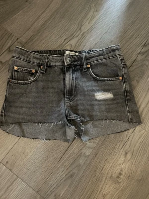 Grå jeansshorts - Snygga grå jeansshorts med rå, fransig kant och slitning på ena benet. Original jeans men har gjorts om till shorts. Kanterna är jämna och fina, säljer bara för att de inte längre är min storlek. Passar mid/low waist. Kontakta för mer information, hjälper hjärna till att besvara frågor💗