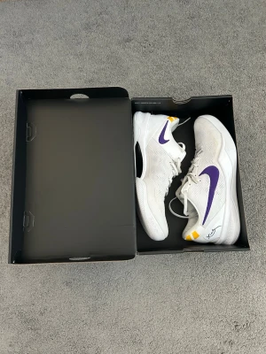 Kobe VII Protro ”Lakers home” (45,5) - Nike Kobe sneakers, färg Lakers home (vitt). Skorna är lätt använda och presterar bra. Skorna är äkta och inkluderar även boxen för dem. Sko storlek är 45,5. Går tyvär ej att frakra produkten. Har du funderingar? Skriv gärna!