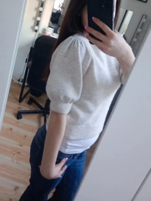 Beige stickad topp med puffärm - Säljer en beige stickad topp med puffärmar och ribbade muddar. Tröjan har en rund halsringning och är något kortare i modellen, vilket ger en trendig look. Perfekt att matcha med jeans eller kjol för en snygg outfit storleken kan ni se på bilderna och den är lite mer beige aktiga i verkligheten 💗☺️