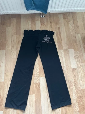 Svarta mjukisbyxor från Juicy Couture - Svarta mjukisbyxor från Juicy Couture med vida ben och hög midja med volangkant. Storlek L men passar som M. Obs har tappat några diamanter på baksidan 