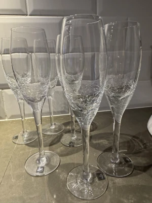6 st champagneglas från Sia - Säljer sex eleganta champagneglas från Sia. Glasen är genomskinliga med ett dekorativt mönster i botten som ger en lyxig känsla. Perfekta för att fira speciella tillfällen med stil. Klassisk form med lång smal kupa och fot. I toppenskick, använda enstaka gång 