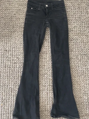svarta cheap monday bootcut jeans  - Säljer ett par svarta cheap monday  jeans från weekday med lila logga bak i midjan. dom är i storlek 23/30. sjukt snygga basic jeans men även fina för speciellt. 