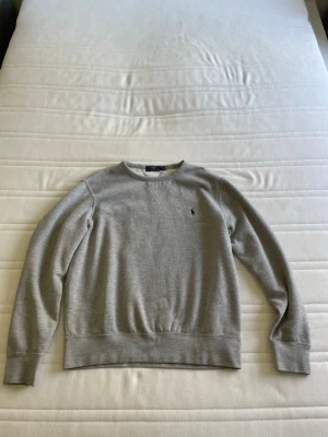  Polo Ralph Lauren Grå sweatshirt - Klassisk grå sweatshirt från Polo Ralph Lauren med rund halsringning och broderad logga på bröstet. Storlek M. Skick 8/10. Pris 250 kronor. 