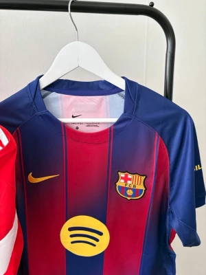 FC Barcelona matchtröja Nike - Säljer en officiell FC Barcelona matchtröja från Nike med klubbmärke och sponsorlogga på bröstet. Tröjan är röd och blå med gula detaljer och har korta ärmar. Perfekt för dig som älskar fotboll och vill visa ditt stöd för Barca.