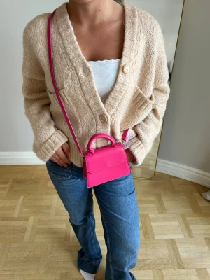 Mini rosa handväska med axelrem💖💖 - Säljer en superfin mini handväska i starkt rosa färg. Väskan har både ett litet handtag och en lång axelrem så du kan bära den crossbody eller i handen. Stilren och trendig design i slätt material, perfekt för att lyfta vilken outfit som helst.
