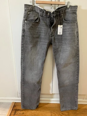 Nya Grå raka jeans New Classic 34/32 Mid Standard - Snygga grå jeans från New Classic i rak modell. Jeansen har klassisk femficksdesign och normalhög midja. Perfekta för en stilren och avslappnad look. Materialet är denim i bomull för en bekväm känsla. Helt nya med prislapp kvar 