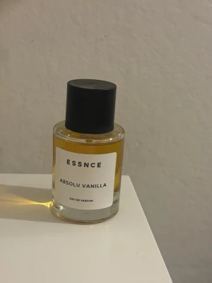 ESSNCE Absolu Vanilla parfym - ESSNCE Absolu Vanilla Eau de Parfum med en rund glasflaska och svart lock. Parfymen har en varm, gyllengul färg och etiketten är vit med svart text. Doften har tydliga vaniljtoner och flaskan känns stilren och modern. Endast testats en gång!