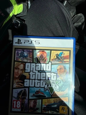 Grand Theft Auto V till PS5 - Grand Theft Auto V till PlayStation 5 med ikoniskt omslag i färgglada toner. Spelet har en blå plastfodral och är märkt med PEGI 18. Perfekt för dig som gillar action, äventyr och öppna världar.