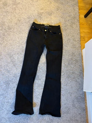 Svarta bootcut jeans med utsvängda ben - Snygga svarta jeans med bootcut-modell och utsvängda ben. Klassisk femficksdesign och knappgylf. Perfekta för dig som gillar en retrostil med modern twist. Jeansen är i ett stretchigt material som sitter skönt hela dagen.