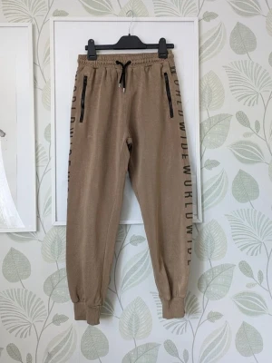 Byxor KappAhl Woxo Storlek 146/152 (152/158) - -Stor I storlek passar 158 eller större 152. - I fint använt skick . - Tyget är i bra skick men trycket på båda sidorna är blekta som på extrabilderna samt finns nopper i midjesnörena . Trycket bak i rumpan är sprucken och fläck finns nedanför trycket jag har ej testat ta bort den förutom detta så är byxorna jättefin i skicket. - Se extrabilderna för att se skick. - Jag kan ha missat någon miniskavank men jag har försökt att granska plagget så gott det går.- Större bilder kan skickas.