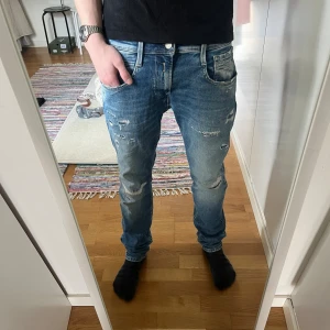 Blå slitna jeans replay - Säljer ett par replay blå slimmade jeans med slitningar och raka ben. Jeansen har klassisk femficksdesign, normal midja och är tillverkade i denim. Perfekta för en avslappnad och trendig look.
