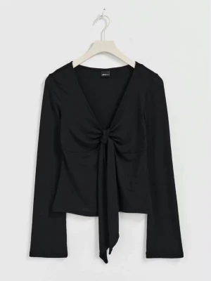 Svart långärmad topp med knyt - Stilren svart långärmad topp från Monki med djup v-ringning och snygg knytning framtill. Toppen har en figurnära passform och är tillverkad i mjuk bomullsmix, perfekt för att lyfta din outfit.