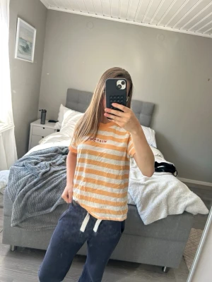 Randig t-shirt i orange och vitt - Säljer en fräsch t-shirt med orange och vita ränder och tryck fram 💞