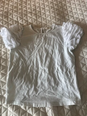 Vit topp med puffärmar - Vit topp med märket angel & rocket. Passar tjejer runt 12 år men skulle gissa på att det är storlek 146/152. Väldigt fint skick förutom att tröjan har fått en svag blå färg från tvätten men det är något man knappt lägger märke till. Pris går att diskutera☺️💞