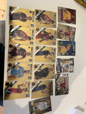 Samling fotbollskort med guldtema - Säljer en samling fotbollskort med guldtema från olika lag och spelare, inklusive specialkort som Cristiano Ronaldo och flera andra kända profiler. Korten har olika färger och motiv, mestadels guld, och är tillverkade i laminerad papp. Perfekt för samlare eller fotbollsintresserade. Priset kan diskuteras 