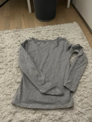Grå långärmad topp från 157 - En enkel och stilren grå långärmad topp från 157. Toppen har en rund halsringning och är tillverkad i mjuk bomull, perfekt för lager på lager eller att bära som den är. Passformen är normal och tyget är tunt och följsamt.