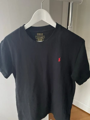 Polo Ralph Lauren T-shirt  - Svart Polo Ralph Lauren T-shirt med röd häst.  Slim fit, S - 165 cm