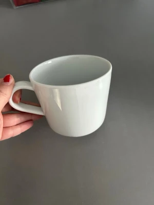 Vit klassisk kaffemugg - En stilren vit kaffemugg i porslin med rund form och rejält handtag. Perfekt för morgonkaffet eller te, enkel design som passar i alla kök. Muggen är helt enfärgad utan mönster eller logga.