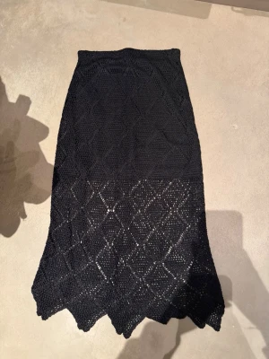 Svart stickad långkjol & Other Stories - Säljer en svart stickad långkjol från & Other Stories. Kjolen har ett snyggt hålmönster och vågig kant längst ner.