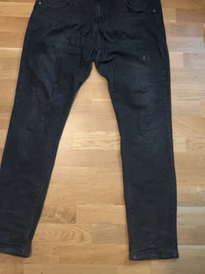 Svarta raka jeans med låg gren - Säljer ett par svarta jeans med rak passform och låg gren. Jeansen har klassiska fem fickor, bakfickor och är tillverkade i ett mjukt denimtyg. Perfekta för en avslappnad streetwear-look.