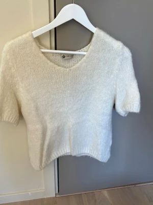 Vit stickad t-shirt från Chelsea - Mysig vit stickad t-shirt från Chelsea butiken i Göteborg med korta ärmar och v-ringning. Tröjan har en mjuk och fluffig känsla, perfekt för lager på lager. Enkel och stilren design som passar till det mesta. Använd ett fåtal gånger men verkligen inget som syns, jätte mysig tröja. Säg till om du ni vill se på😊står ingen storlek på men skulle säga att det är en xs/s, nypris ca 500kr 