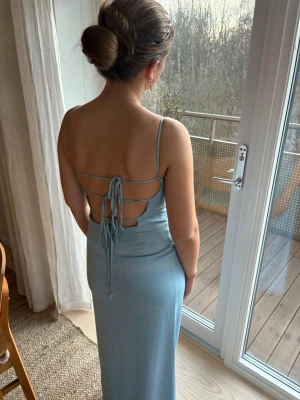 Ljusblå Satinklänning NA-KD - Säljer denna superfina, ljusblå klänningen i satin från NA-KD.🩵 Den har en draperad ringning (cowl neck) fram och en öppen rygg med snörning som du kan justera själv!  • Storlek: 38 (Passar även 36/40 tack vare justerbar rygg)  Skick: Klänningen är lite nopprig/sliten på vissa ställen. (Se bilder) Detta är dock inte särskilt märkbart när man bär själva klänningen. En större defekt är dock att en söm har gått upp vid ena snöret i ryggen. Men detta kan lagas enkelt hemma. Därav ett billigt pris!🌟