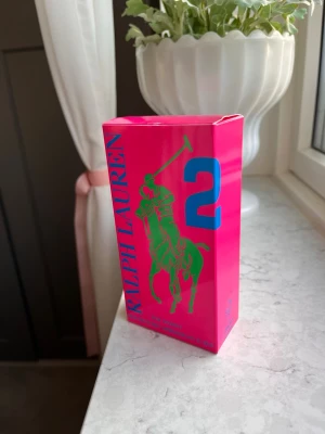 Ralph Lauren Big Pony 2 parfym - En ny och oanvänd parfym från Ralph Lauren. Är den rosa damparfymen i största storleken, 100ml. Parfymen har ett snyggt utseende i en rosa färg, en grön detalj och en blå tvåa på baksidan.