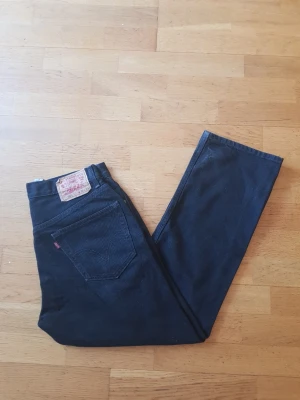 Svarta Levi's 505 jeans straight fit - Säljer ett par svarta Levi's 505 jeans med straight fit och klassisk femficksdesign. Jeansen har en tydlig läderpatch bak i midjan och den ikoniska röda Levi's-taggen på bakfickan. Tillverkade i slitstark denim, perfekta för en clean och tidlös look.