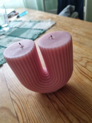 Rosa U-format blockljus - Unikt rosa blockljus i U-form med räfflad yta och två vekar. Ljuset är tillverkat av vax och har en modern, dekorativ design som sticker ut i rummet. Perfekt som inredningsdetalj för dig som gillar trendiga former och färger.