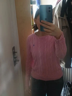 Rosa kabelstickad tröja Gant - Säljer en rosa kabelstickad tröja från Gant med rund halsringning och lång ärm. Tröjan har ett diskret Gant-märke broderat på bröstet och är gjord i mjukt material som sitter snyggt på kroppen. Perfekt för dig som gillar klassisk preppy stil.