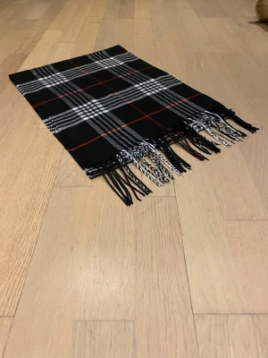 En svart rutig halsduk.  - En svart rutig halsduk, den är helt ny nästan aldrig använd. 