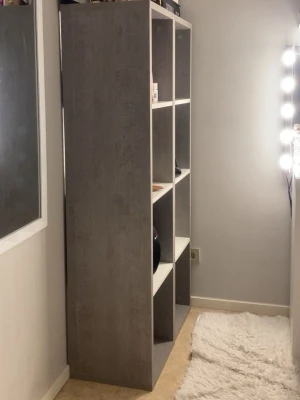 Gråvit hylla med sex fack - Säljer en stilren hylla i grått och vitt med sex öppna fack. Perfekt för förvaring av böcker, skor eller dekorationer. Hyllan har en modern design med raka linjer och är tillverkad i trälaminat. HÄMTAS ENDAST 