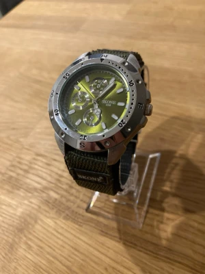 Skone Green Diver 42mm Herrklocka - Säljer en snygg grön hulk-inspirerad dykarklocka från Skone i oanvänt skick enligt bilder. Plasten kvar på baksidan och inga repor. Fungerar bra, dubbelt original Nato-armband, datumvisare, mineralglas, roterande dykarring, quartz urverk, vattentät, självlysande osv. Behöver bara nytt batteri. Modell: 6058.  Nypris: 400 SEK Mitt pris: 289 SEK  Skickas snabbt och spårbart. Skriv vid frågor och se gärna mina andra annonser!