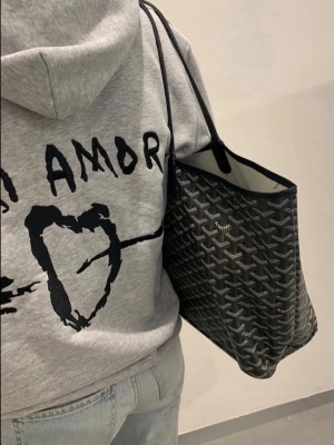 Grå hoodie från Mira Paris med tryck mi Amor  - Snygg grå hoodie från Mira Paris med svart tryck framtill där det står 'AMOR' och ett hjärta. Hoodien har huva med dragsko och är tillverkad i mjukt bomullsmaterial. Perfekt för en avslappnad och trendig look.