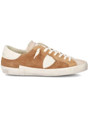 Bruna Philippe Model sneakers i mocka - Vi har dem i 44 och 45. Snygga sneakers från Philippe Model i brunt mocka med vita detaljer och vit sula. Skorna har en klassisk låg profil, vita skosnören och en ikonisk sköld på sidan. Perfekta för dig som gillar en stilren och avslappnad look.