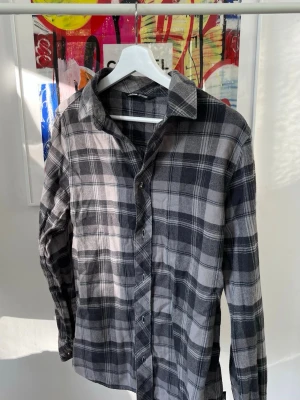 Rutig flanellskjorta från The North Face - Snygg rutig skjorta från The North Face i svart och grått. Skjortan har klassisk krage, knäppning framtill och långa ärmar. Perfekt för en avslappnad och cool stil. Tillverkad i mjukt bomullsmaterial.