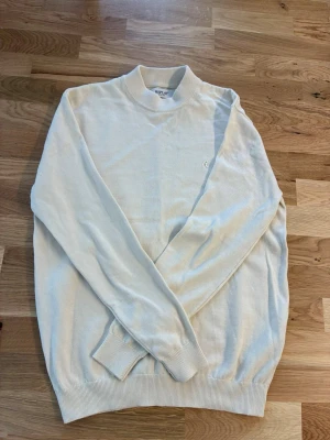 Vit stickad tröja från Replay - Snygg vit stickad tröja från Replay med rund halsringning och diskret logga på bröstet. Tröjan har långa ärmar och ribbade muddar vid ärmslut och nederkant. Perfekt för en clean och stilren look.