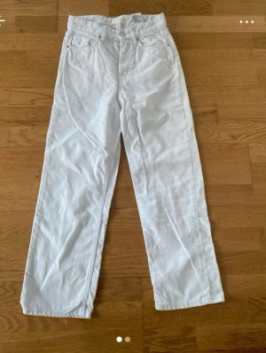 Vita raka jeans från H&M, strl 36 - Snygga vita jeans från H&M i rak modell med klassisk femficksdesign och normal midja. Perfekta att styla med en crop top eller hoodie. Jeansen är i ett mjukt bomullstyg och har knapp- och dragkedjestängning framtill.