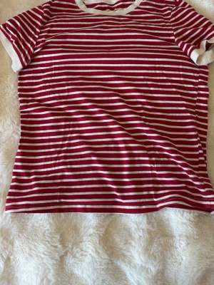 Rödvit randig t-shirt - Snygg t-shirt med röda och vita horisontella ränder och kontrasterande vita muddar vid hals och ärmslut. Perfekt för en avslappnad och trendig stil. Klassisk passform och korta ärmar. Skriv för frågor❤️ 