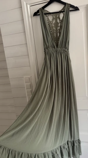 Sabo skirt maxiklänning i stl S helt ny - Lång vacker klänning med djup V-ringning och spetsrygg från Sabo skirt  Helt ny men det finns en skada på höger axelband se bild nr 6  Längd - ca 145 cm