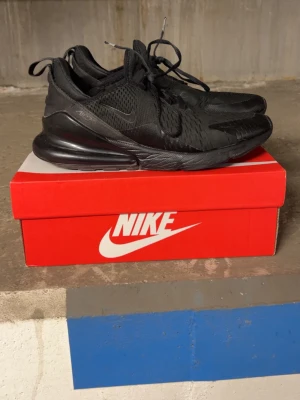 Nike Air Max 270 - Nike Air Max 270 sneakers i helsvart med mesh-ovandel och synlig Air Max-dämpning i hälen. Snygg sportig design med svarta snören och diskreta loggor. Perfekta för dig som gillar en clean och stilren look. Lätta och bekväma med modern känsla. Passar 42-43,5