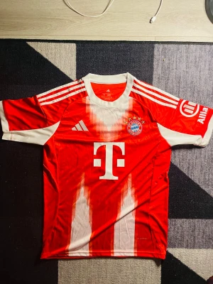 Bayern München matchtröja Musiala #10 - Röd och vit Bayern München matchtröja  med Musiala och nummer 10 på ryggen. Perfekt för fotbollsfans som vill visa sitt stöd på läktaren eller planen.