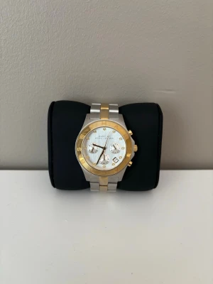 Marc by Marc Jacobs klocka guld/silver - Snygg klocka från Marc by Marc Jacobs i silver och guld med länkarmband i metall. Urtavlan är vit med gulddetaljer och tre mindre urtavlor. Klassisk och stilren design med logotyp runt boetten. Perfekt accessoar för att lyfta din outfit. Nybytta batterier