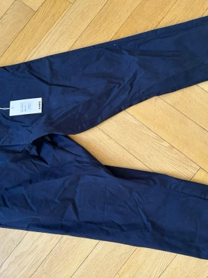 Mörkblå chinos, Oanvända Etikett kvar - Snygga mörkblå chinos med rak passform och klassisk design. Tillverkade i ett mjukt och bekvämt material som passar perfekt till en avslappnad men stilren look. Byxorna har diskreta fickor och bälteshällor. Etiketten sitter kvar och är oanvända. NYPRIS 899