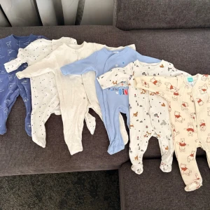 Söta babypyjamasar i olika färger - Flera mjuka och mysiga baby-pyjamaser i bomull med olika mönster som djur, stjärnor och dinosaurier. Färgerna är blå, vit, beige och gräddvit med tryck. Perfekta för sköna nätter och lugna morgnar. Vissa är oanvända, endast tvättat innan ev användning men glömt bort dom, och vissa använda endast 1-2 ggr  Strl 62