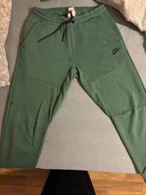 Gröna niketech byxor - Gröna nike tech byxor i en unik färg, några synliga fläckar fram på byxorna