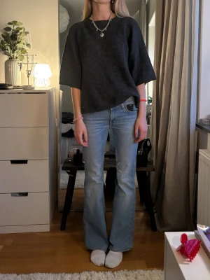 Mörkgrå oversized stickad tröja - Mörkgrå stickad tröja med oversized passform och korta, vida ärmar. Tröjan har en rak och avslappnad siluett, perfekt att styla med jeans eller kjol. Materialet ser mjukt och bekvämt ut, och färgen är lätt att matcha med andra plagg.